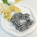 Primer plano de coleteros de algodón con cuadros vichy amarillos y negros en un plato blanco - Cuadros Grandes Negro