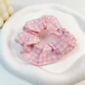 Primer plano de un coletero de algodón a cuadros rosas y blancos en un plato blanco - Grandes Cuadros Rosas