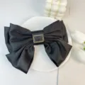 Close-up detail of large black satin triple-layered bow hair clip with a gold buckle - With Metal Buckle / Black