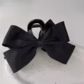 Close-up of elegant black ribbon bow claw clip on white ceramic plate - Glossy Wide Ribbon / Black