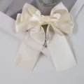 Detailed view of elegant cream satin ribbon bow hair clip with smooth fabric texture - Off White