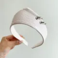 Detailed macro view of a white textured leather headband with stylish silver rings. - Crown Leather Ring Style / Off White