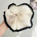 Gedetailleerd beeld van een crème mesh scrunchie met zwarte ruches voor het haar - Lichtgeel