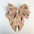 Détail d'un nœud en mousseline plissée rose avec motif floral et perles élégantes. - Rose Pêche