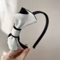 Primo piano di un elegante cerchietto con fiocco in velluto bianco e nero da donna - Beige + bow headband