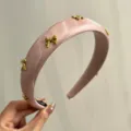 Close-up of pink satin padded headband featuring gold metal bow embellishments - Pink With 7 Bows
