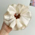 Dettaglio di scrunchie in raso crema con bordo di delicate perline di cristallo - Stile Beige / Bordo in Strass