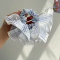 Close-up detail of a blue and white checkered ruffled scrunchie hair tie for daily hair styling - Plaid Ruffle Style / Sky Blue