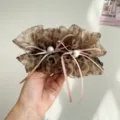 Gros plan d'une pince banane en tulle léopard avec des rubans roses et des perles. - Pince Banane Nœud Perle Artificielle / Léopard Jaune