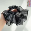 Close-up of a black and white striped oversized ruffled organza hair scrunchie. - Plaid Ruffle Style / Black Blue