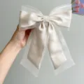 Close-up of a romantic champagne organza bow hair clip with elegant satin finish - Bowknot Spring Clip / Off White