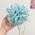 Macro detailed view of a forest style floral print scrunchie with light green ribbons - Bow Streamer Style / Blue