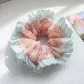 Close-up detail of a pastel mesh scrunchie with light blue ruffles and floral print - Pink Floral Pleated Edge