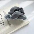 Nahaufnahme eines plissierten Haargummis mit grauem Stoff und blauem Rüschenrand - Geraffte Haarklammer