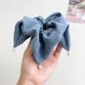Detailansicht eines blauen Stoff-Haargummis mit eleganten weißen Diamantanhängern - Blau