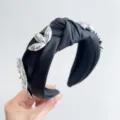 Detailed view of a black knotted wide headband decorated with silver metallic flowers - 金属花挂件打结发箍 / Purple