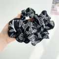 Detailed view of a retro floral pattern oversized black and white hair scrunchie. - Black Abstract Print