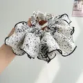 Close-up detail of white and black speckled ruffled scrunchie with elegant black hem. - White Polka Dot Floral