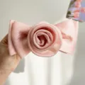 Elegant pink pleated fabric hair clip featuring a large rose and bow design held in hand - Pink Rose Bow Spring Clip