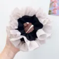 Detail of a balletcore pink lace scrunchie with layered fabric held in hand - Black + Pink