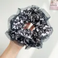 Close-up of large floral pleated scrunchie featuring elegant grey mesh trim detail - Black With Floral Mesh Edge