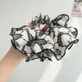 Macro view of vintage black and white embroidered lace pattern on a large fabric scrunchie. - White Abstract Print
