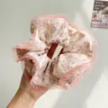 Detailed view of a soft floral print scrunchie with pink pleated edges held in hand - Beige With Floral Mesh Edge