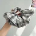 Detail shot of a black and white plaid ruffled scrunchie hair accessory. - White