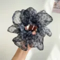 Gros plan d'un grand chouchou en maille à motif léopard gris tenu dans la main d'une femme - Chouchou Mince Plissé / Imprimé Léopard Gris