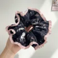 Gros plan d'un chouchou noir avec motif de cheval et bordure en dentelle rose - Chouchou En Dentelle À Imprimé Floral