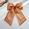 Detail view of shimmering orange organza butterfly bow hair clip with long streamers - Bowknot Spring Clip / Orange