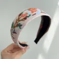 Macro view of retro ethnic floral embroidery on a wide Bohemian cloth headband. - Wide Headband / Pink Floral
