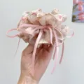 Detailed view of an elegant floral print hair scrunchie with long pink ribbon streamers - Bow Streamer Style / Off White