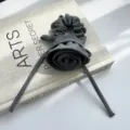 Nahaufnahme eines grauen plissierten Rosen-Haargummis mit eleganten langen Bändern auf Buch - Rosenblüten Haargummi