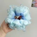 Nahaufnahme eines hellblauen Haargummis aus Netzstoff mit Rüschen für Damenfrisuren - Blau