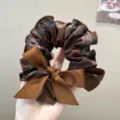 Detailed macro view of a brown plaid fabric scrunchie with a large satin ribbon bow tie - L / Brown Plaid Bow Hair Tie
