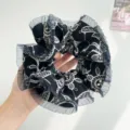 Close-up of black oversized scrunchie with lace edge and white patterns - Black With Print Mesh Edge