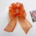 Detailansicht eines lebhaften orangefarbenen Haargummis aus Organza mit Schleife - Haargummis aus Netzstoff mit Schleife / Orange