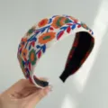 Close-up view of a vintage bohemian floral embroidered wide fabric headband for women - Wide Headband / Orange Green Floral