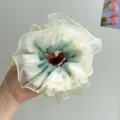 Nahaufnahme eines großen Rüschen-Organza-Haargummis mit eleganten gelben Nahtkanten - Grün