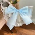 Detail view of an oversized light blue organza bow hair clip with white lace embroidery - Blue bow hair clip