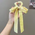 Detail view of a yellow velvet bow scrunchie with elegant long ribbons for hair - Bow Streamer Style / Yellow