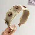 Détail d'un serre-tête en raphia crème orné de fleurs à paillettes marron et de cristaux - Style Fleur Plissée Beige