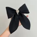 Detailed view of elegant black satin bow hair clip featuring a white camellia flower - Black With Flower Bow Spring Clip