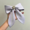 Close-up of large lilac satin bow hair clip with white camellia flower and pearl detail - Light Purple With Flower Bow Spring Clip