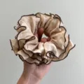 Primer plano de un coletero beige con volantes y elegantes bordes ribeteados café oscuro. - Coletero a Capas / Albaricoque