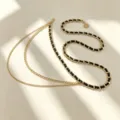 Ceinture chaîne en métal multicouche avec tressage en cuir noir et pendentif soleil. - Chaîne de Taille Tissée Dorée avec Pendentif Soleil Style Glands