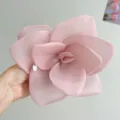 Macro view of a large pink organza rose hair accessory with a decorative metal tag - Pink