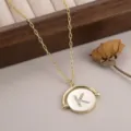 Gros plan d'un collier pendentif rond tournant doré avec la lettre K sertie de strass brillants. - 镶钻字母K款