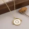 Détail en gros plan du collier à pendentif rond doré avec lettre G en cristal - 镶钻字母G款